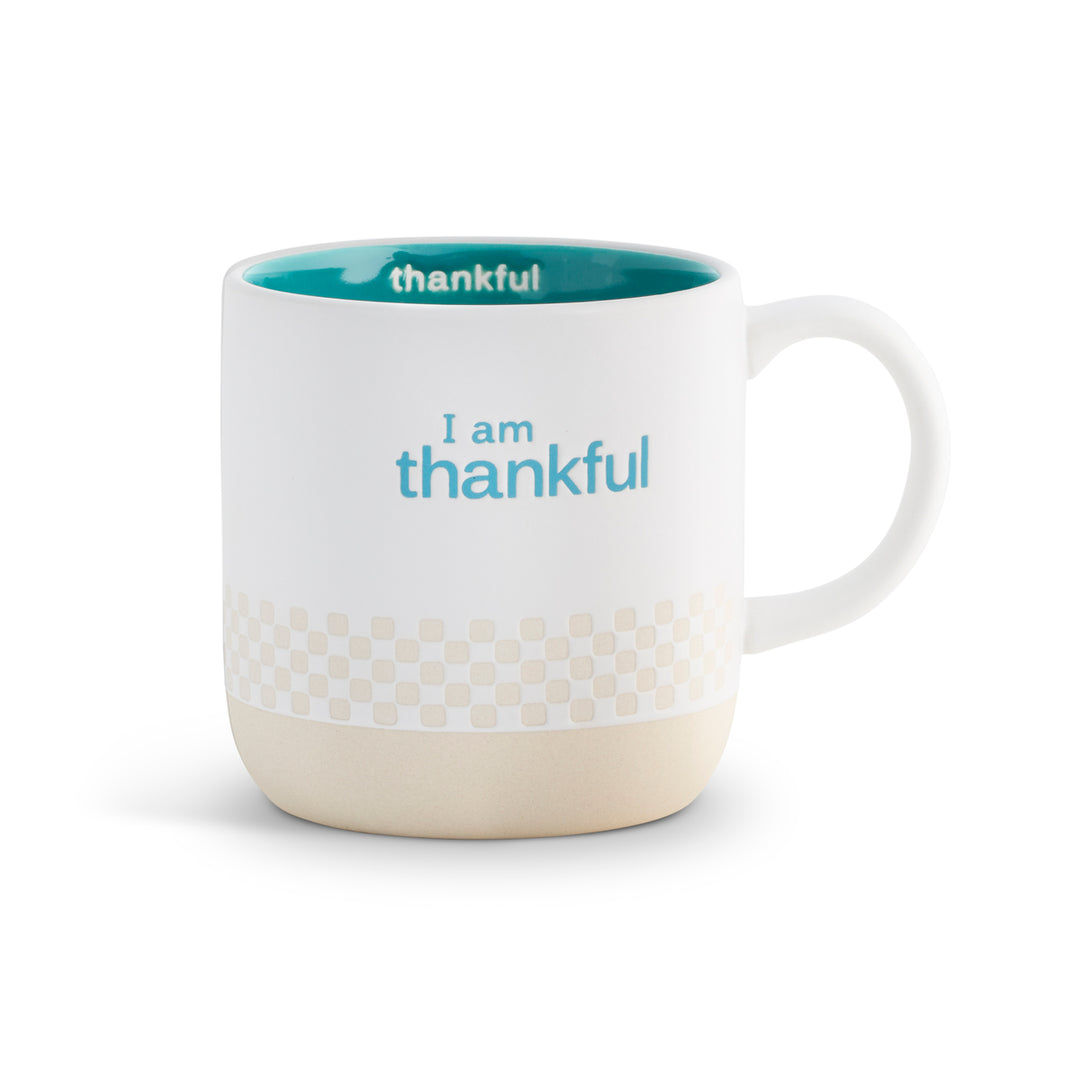 White mug with blue interior and text 'I am thankful' on a white background