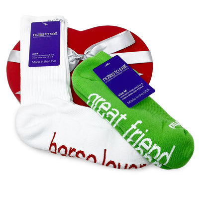 horse lover white socks with rust words and I am a great friend green socks with white words on top of a red heart box with silver ribbon